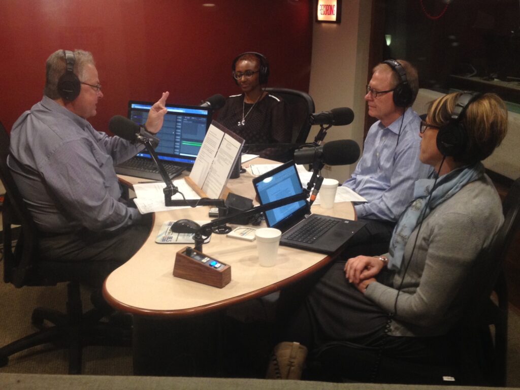 Photo of four people recording a conversation into microphones