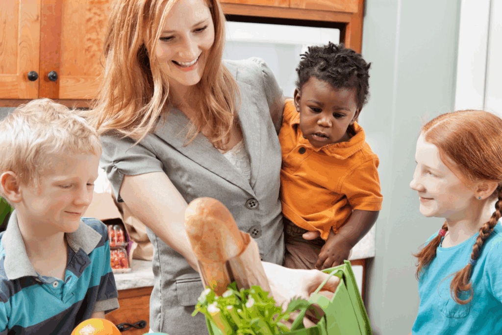 Photo of a mother and her three children standing in the kitchen as she grabs produce out of a grocery bag