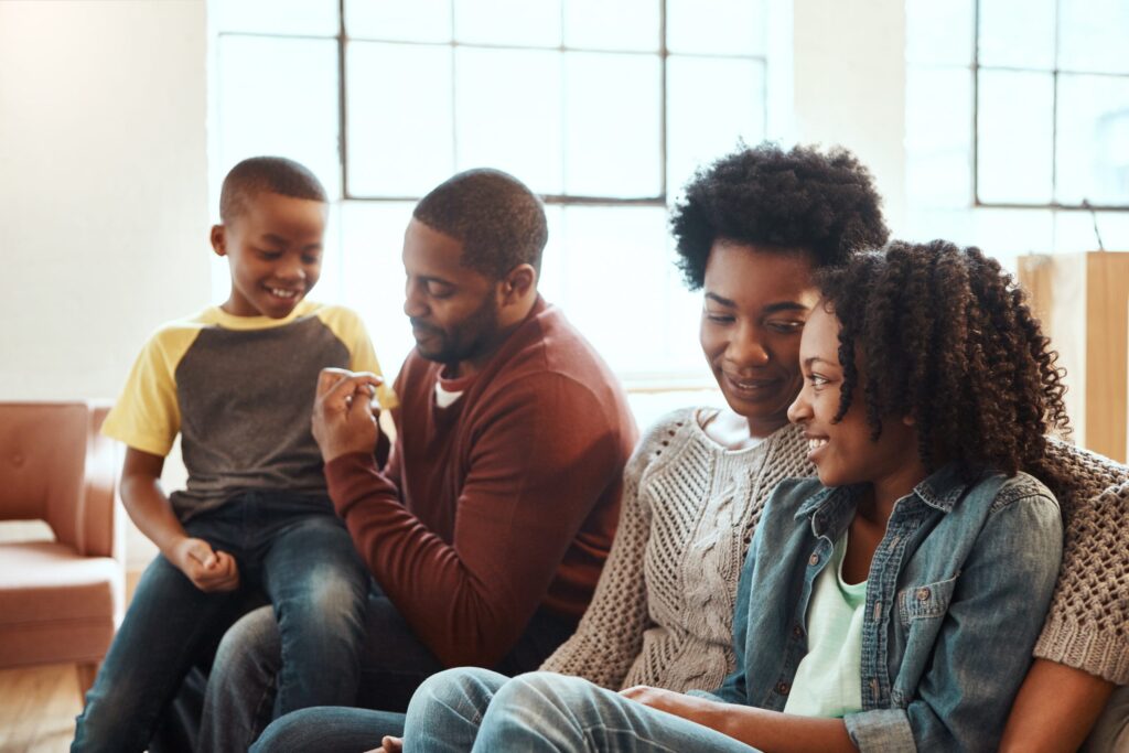 Photo of a 4 person family sitting together on a couch