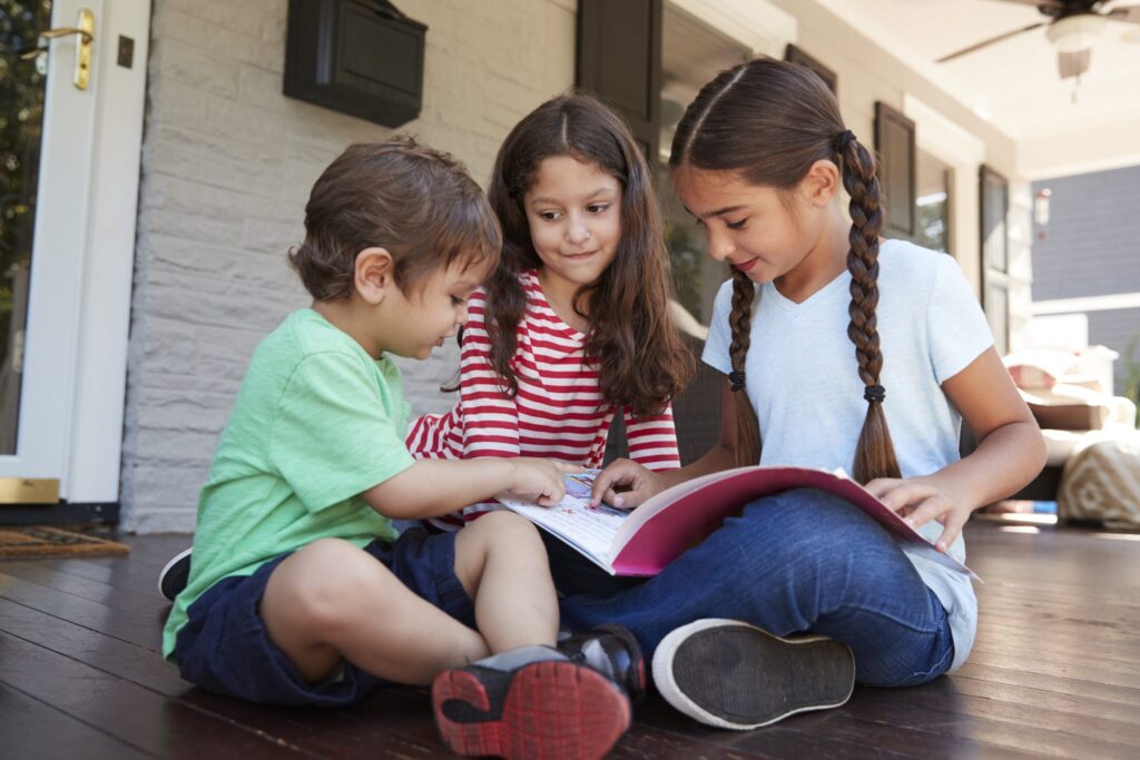 Photo of three children sitting and reading a book