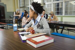 Photo of a young student sitting alone at lunch