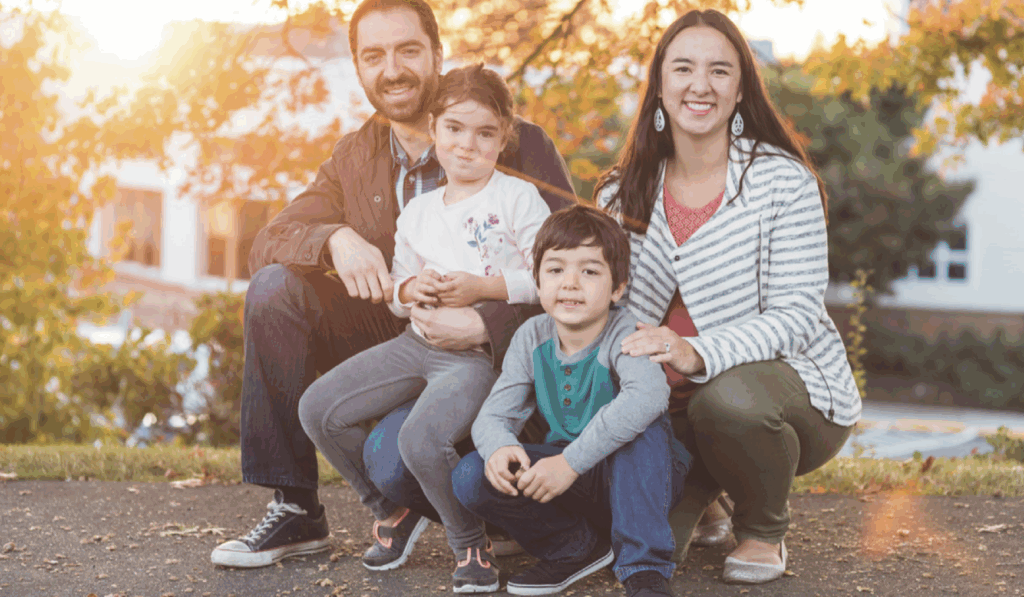 Photo of a mom and dad kneeling on the ground with their son and daughter