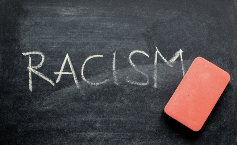 Graphic of a chalkboard with "RACISM" written in white getting erased by a pink eraser