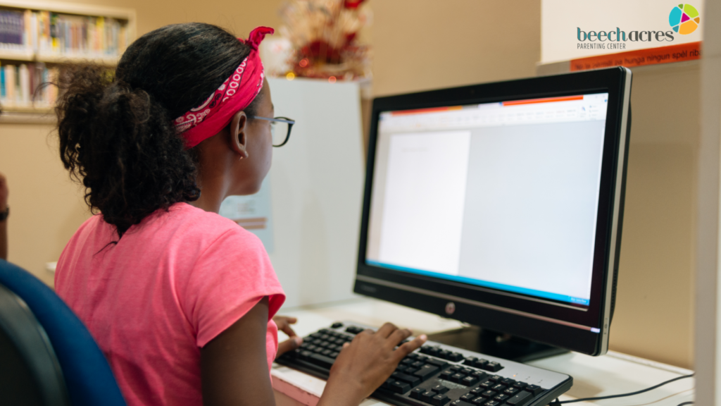 Photo of a young girl typing on a computer keyboard while looking at a computer screen