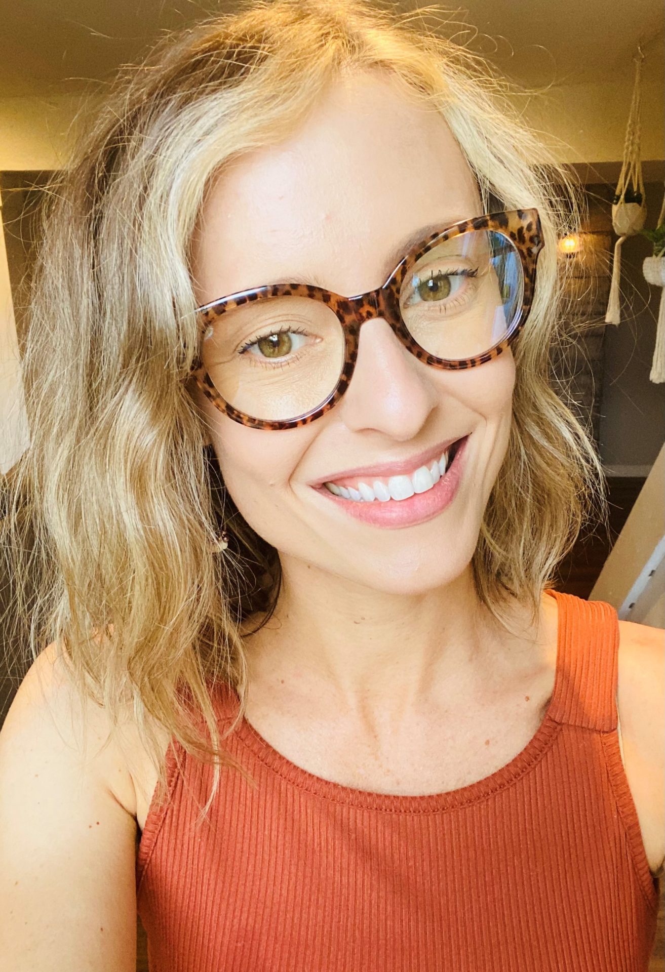 Photo of a woman wearing an orange tank top and brown glasses