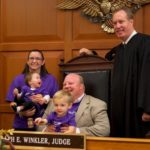 Photo of a family sitting together with a judge on adoption day