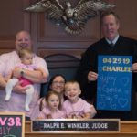 Photo of a family sitting by a judge on Charlee's adoption day