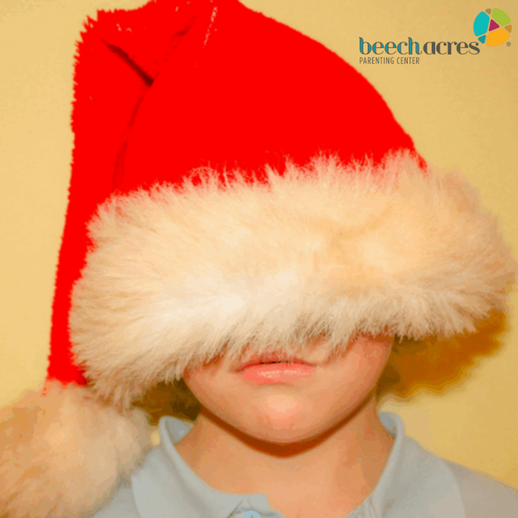 Photo of a young boy with a red Santa hat covering the majority of his face while he frowns