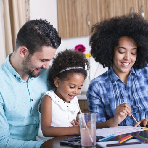 Photo of a mother and father painting with their daughter